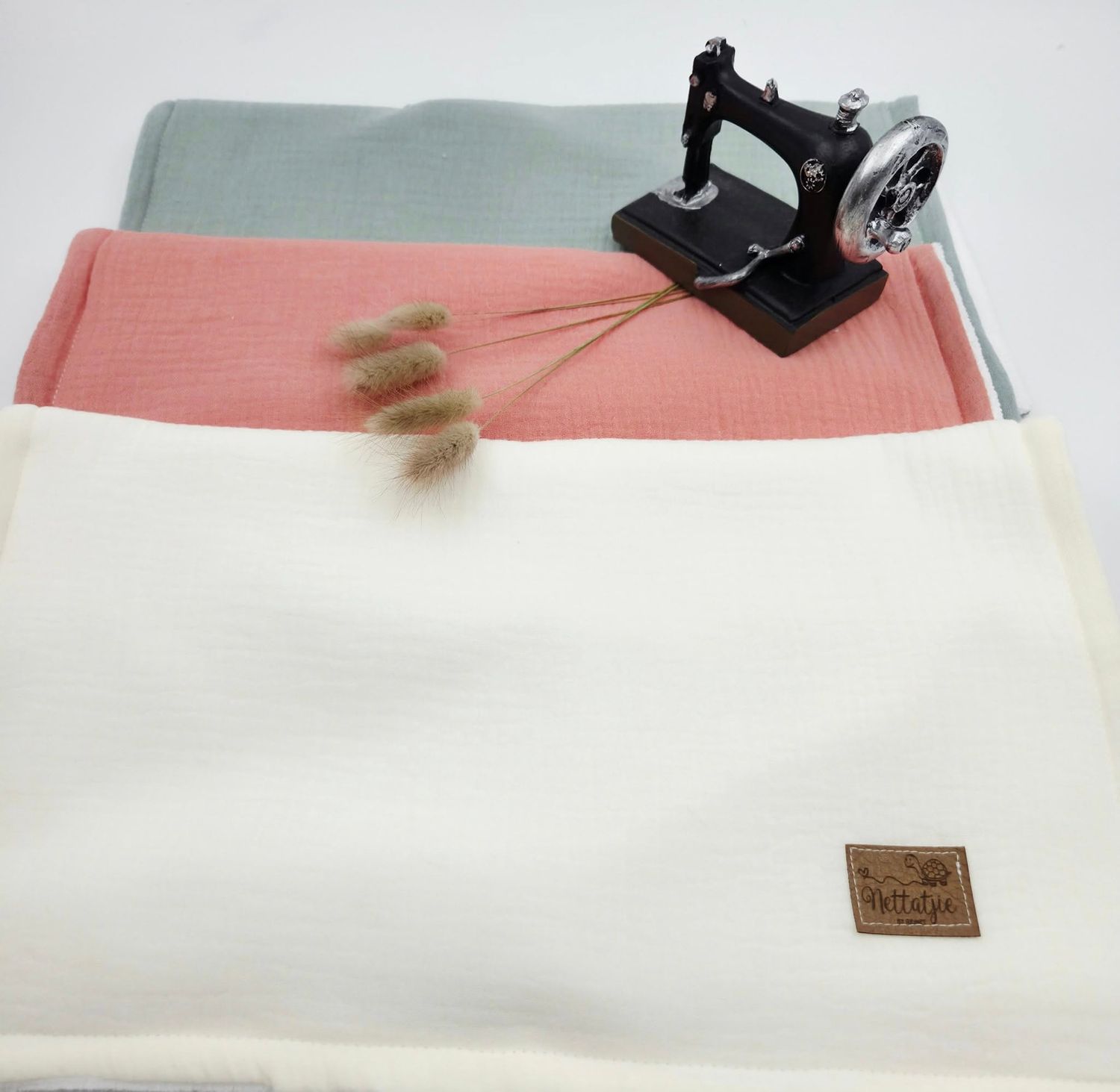 White and coral baby blanket with leather tag detail shown in multiple views.