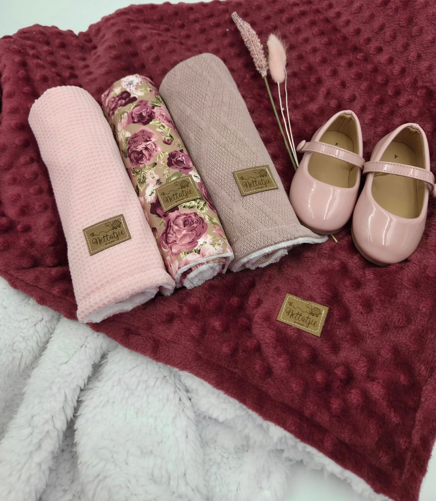 Burgundy minky blanket with pink accessories and shoes arranged on white surface.