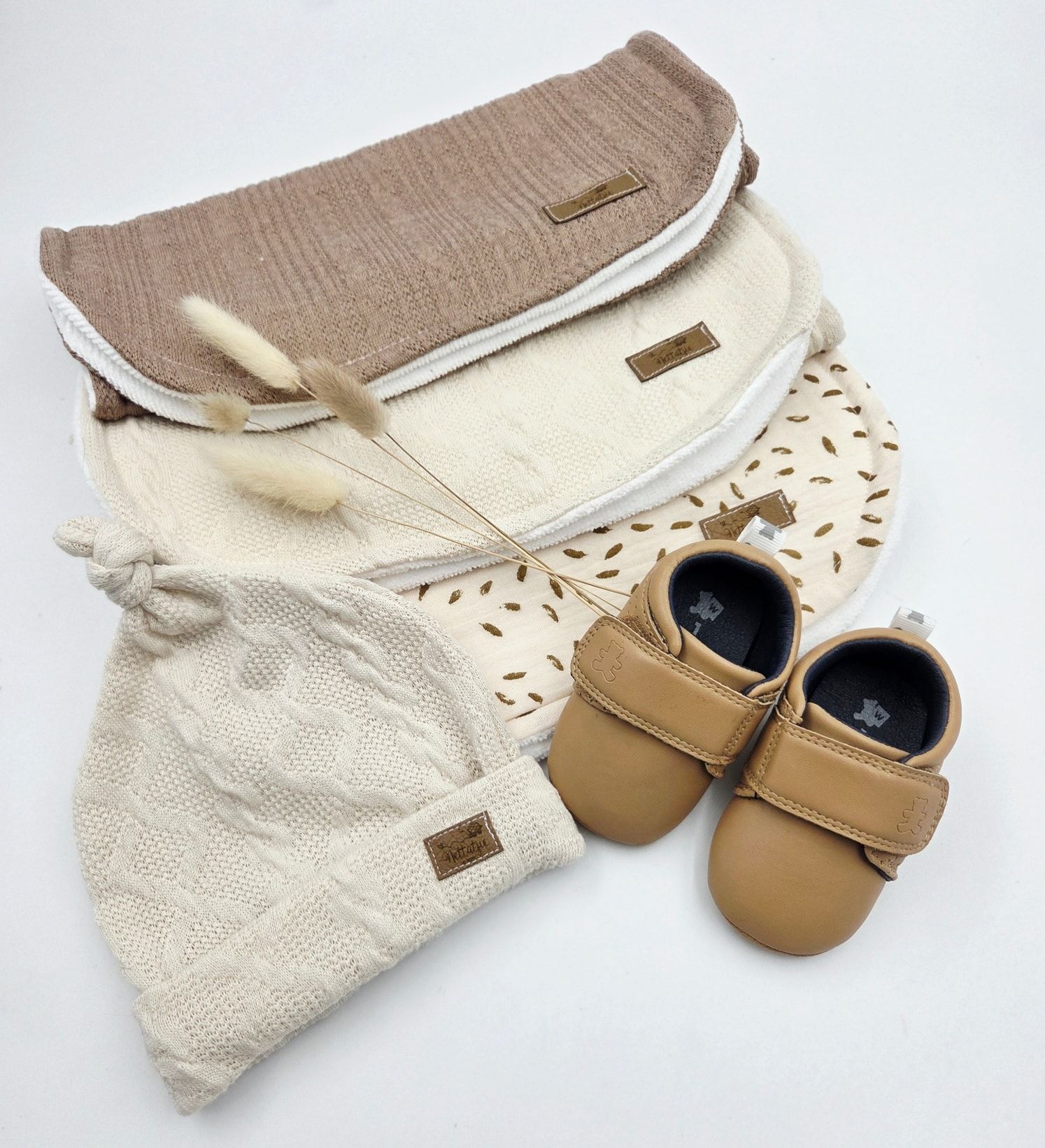 Beige knit baby blanket with tan leather booties displayed on white background.