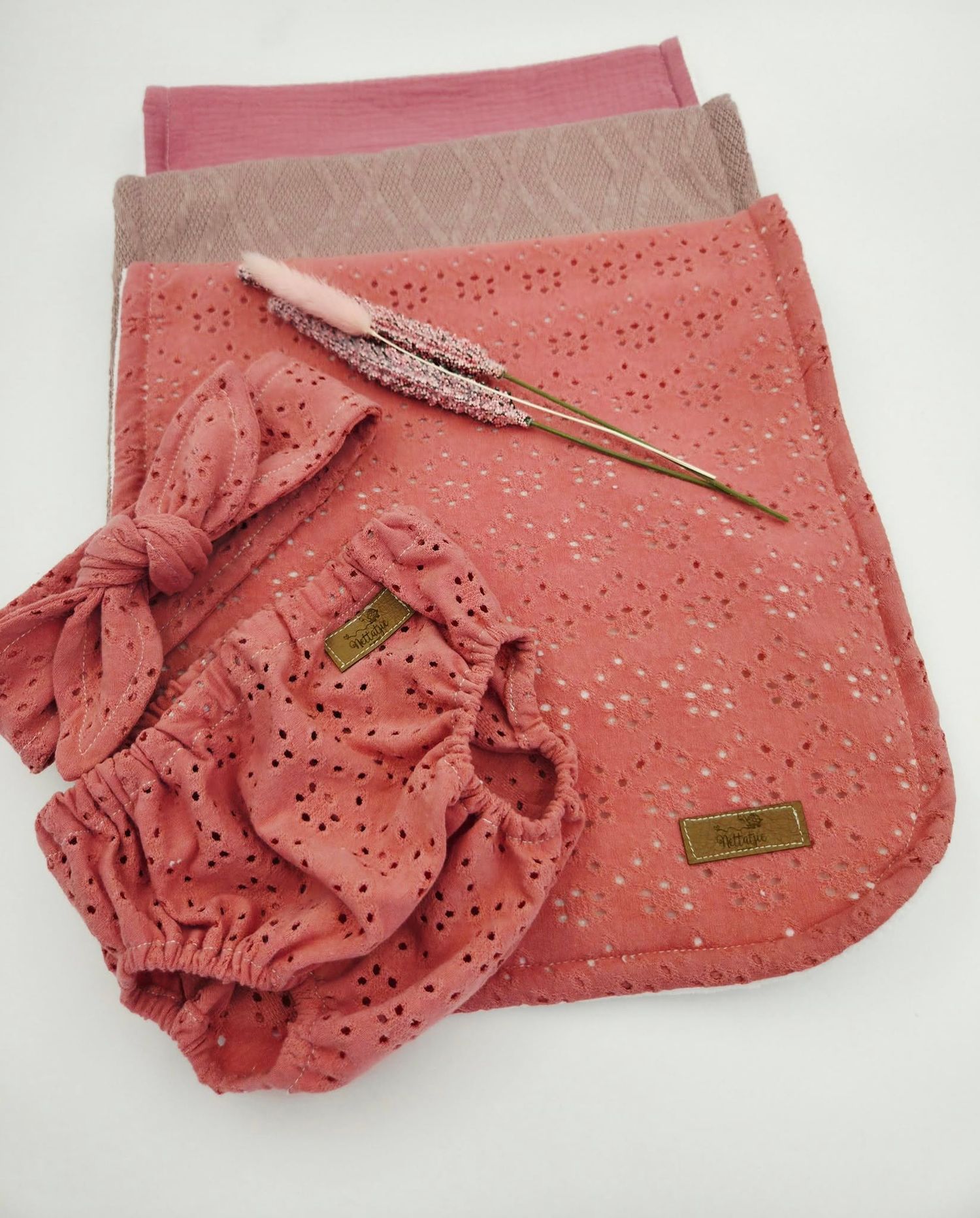 Coral eyelet fabric baby blanket with decorative ruffle detail.