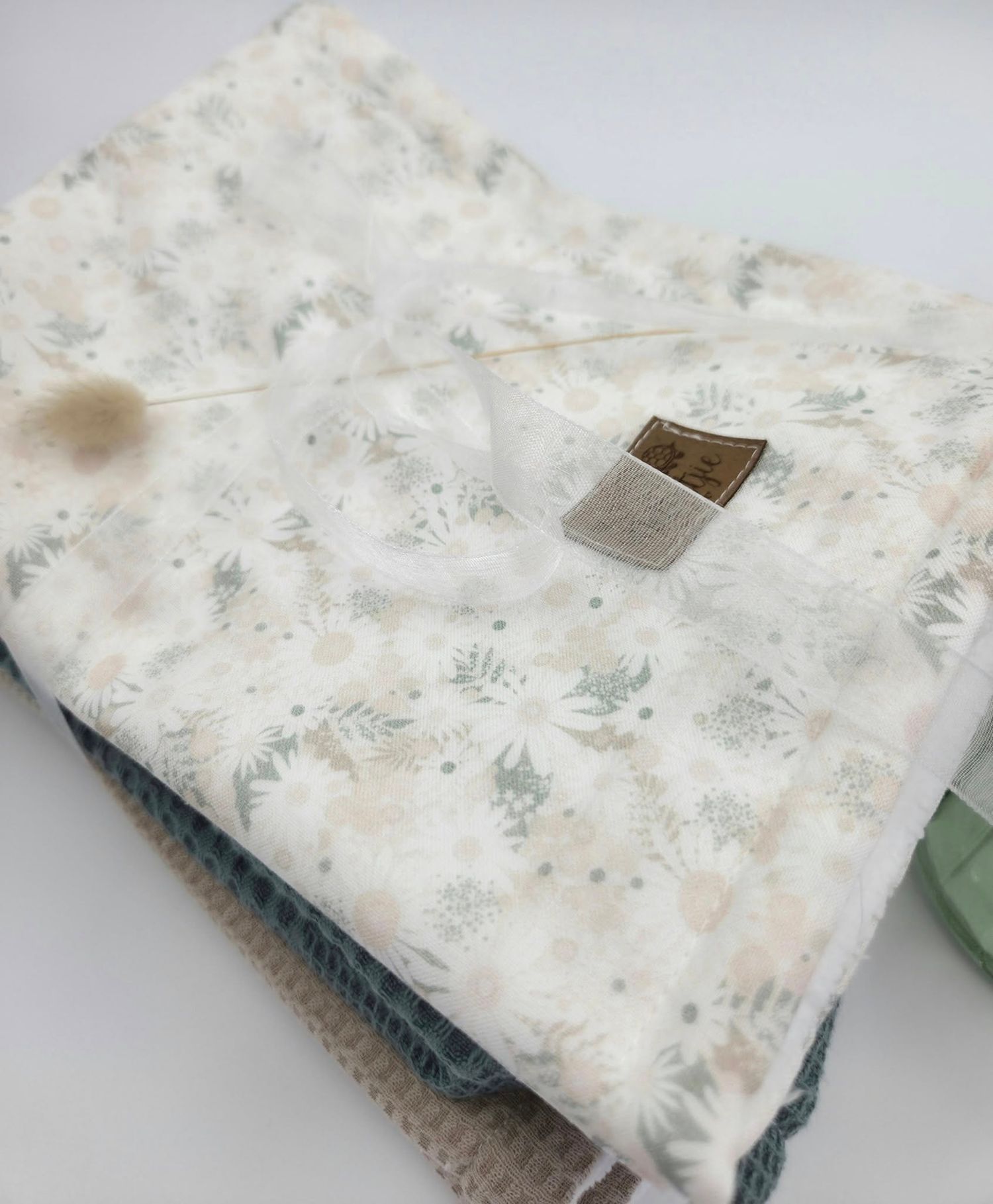 Delicate floral print baby blanket in white and gray tones shown from multiple angles.