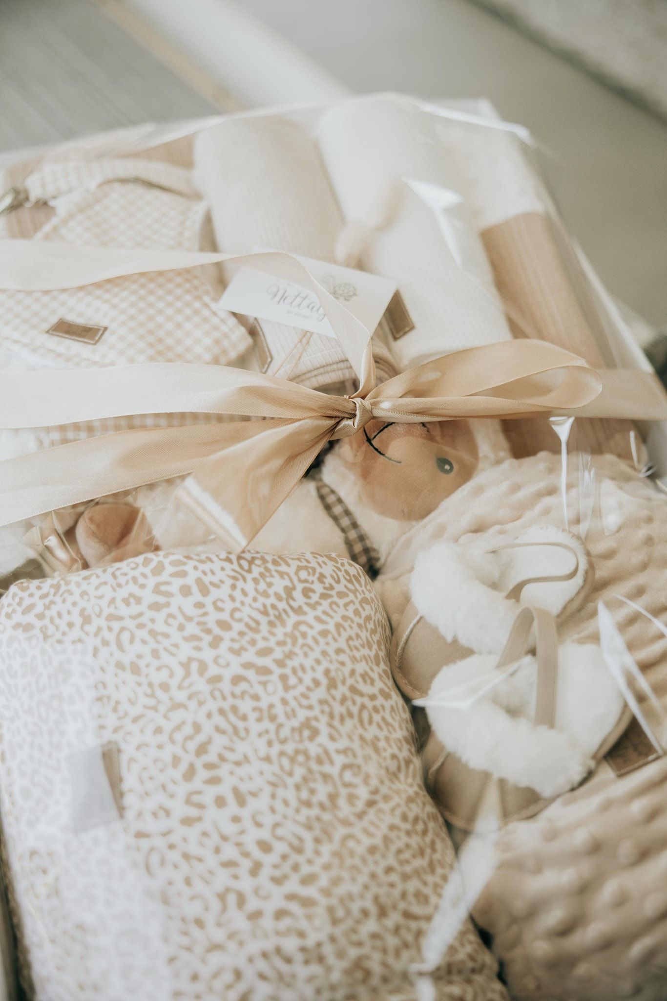 Soft neutral-toned gift wrapping with beige ribbon and delicate lace patterns in an elegant arrangement.