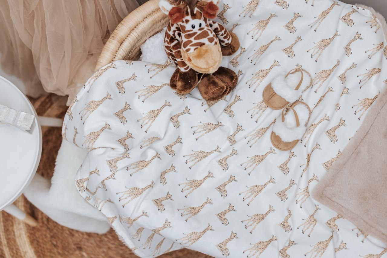 A cozy nursery corner with white and beige decor featuring a rocking chair, crib, and delicate wall decorations.