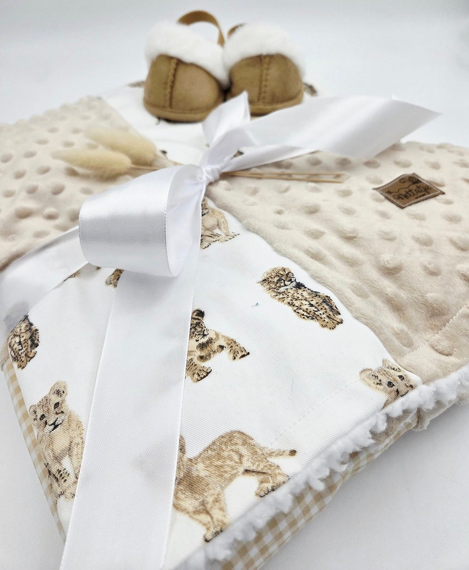 Cream colored minky baby blanket with puppy print pattern tied with white ribbon.