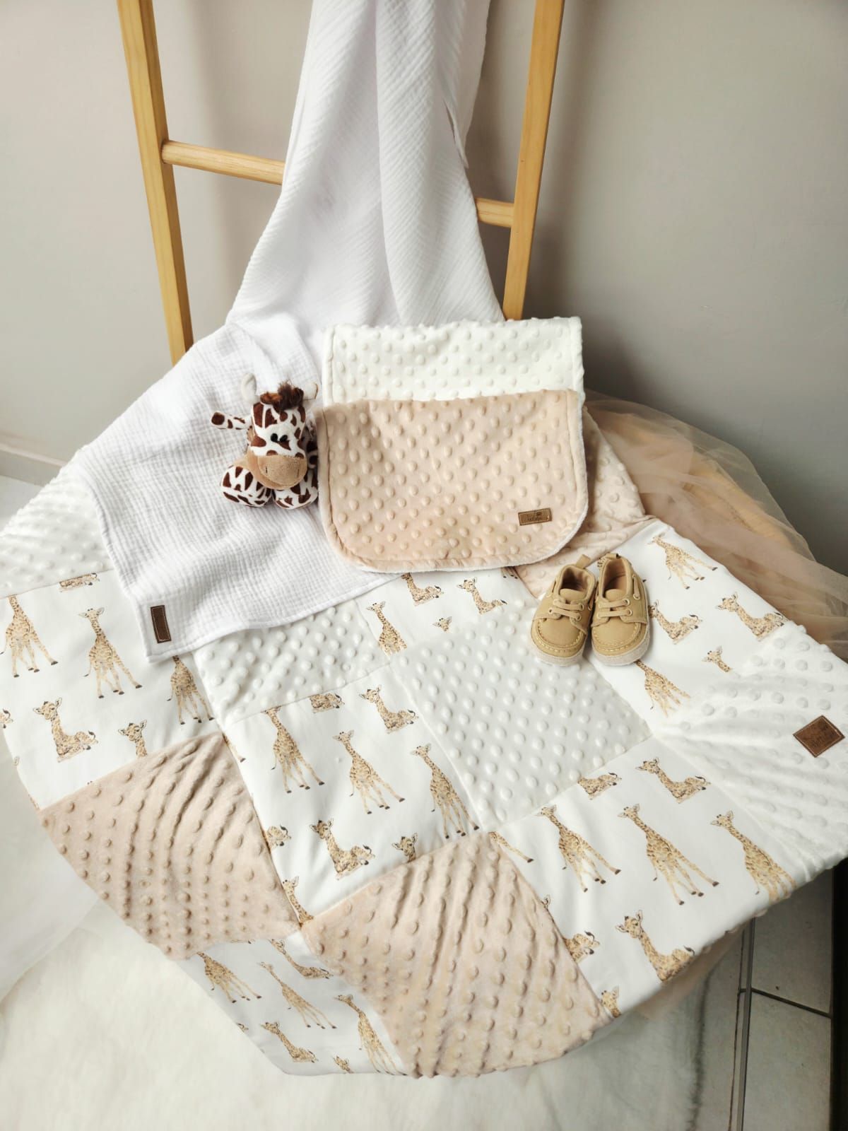 A collection of soft minky blankets in neutral beige and cream colors with woodland animal prints displayed on a chair.