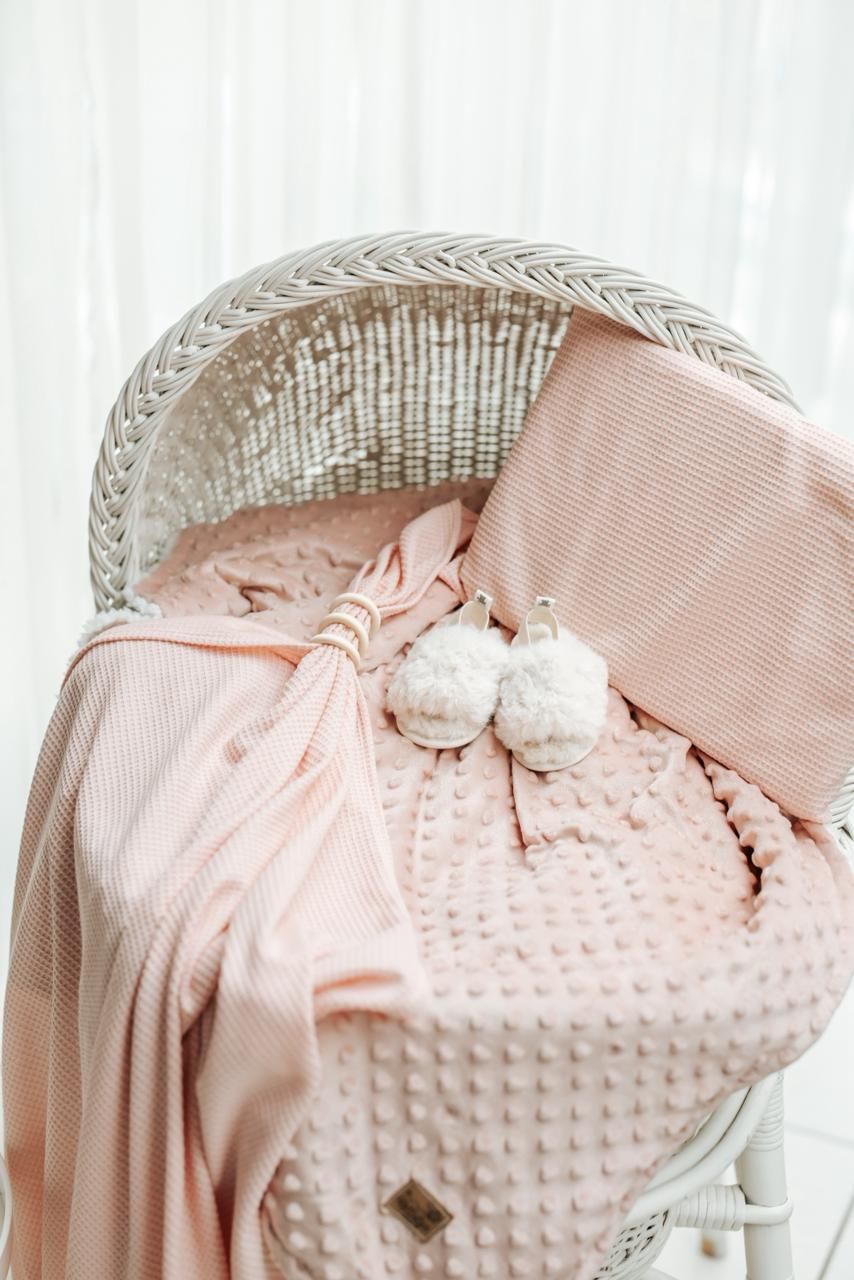 Close-up views of pink minky fabric with textured dots and delicate bow details in soft lighting.