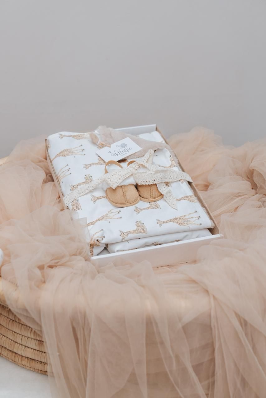 Baby blanket with unicorn print pattern nestled in peach tulle fabric on a woven basket.