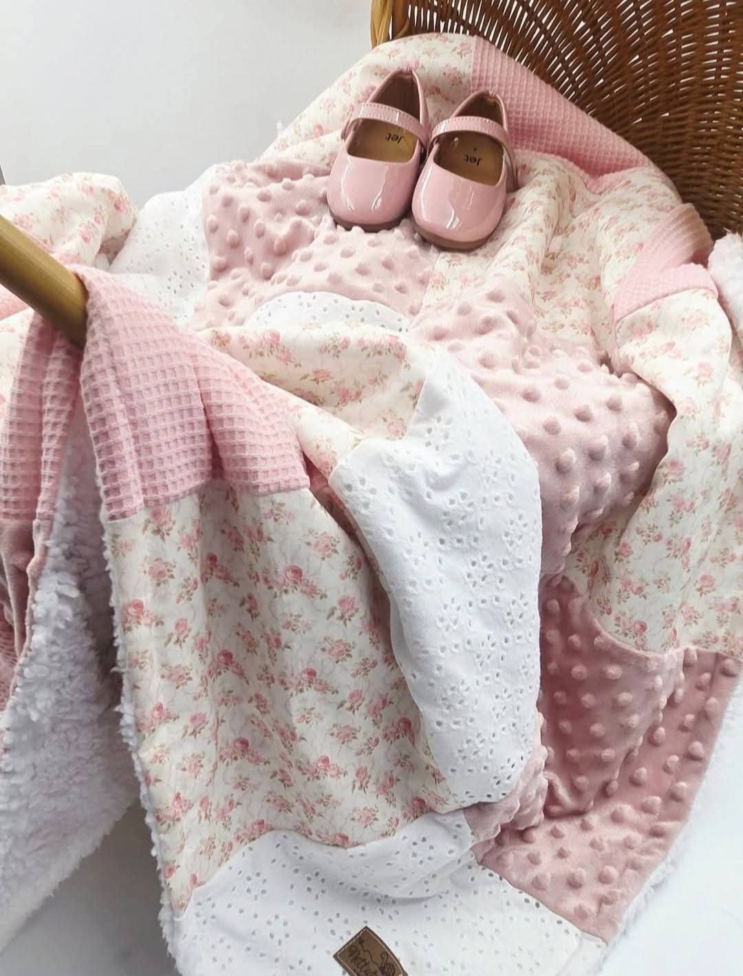 Pink floral baby blanket with minky dot fabric and eyelet lace, displayed in wicker basket with pink Mary Jane shoes.