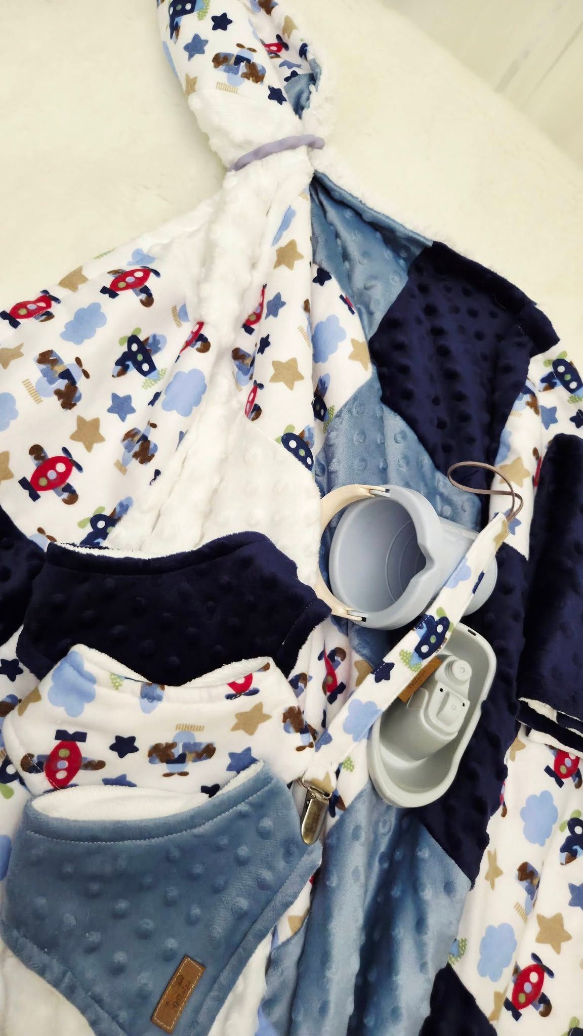 Baby boy gift set with airplane print blanket, navy minky quilt, blue bib, pacifier clip, and baby shoes.