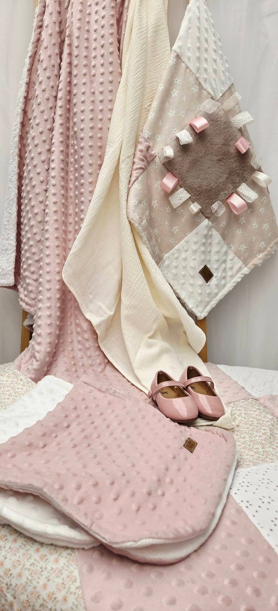 Pink and cream baby blankets with textured minky dots, patchwork lovey, and pink Mary Jane shoes displayed together.