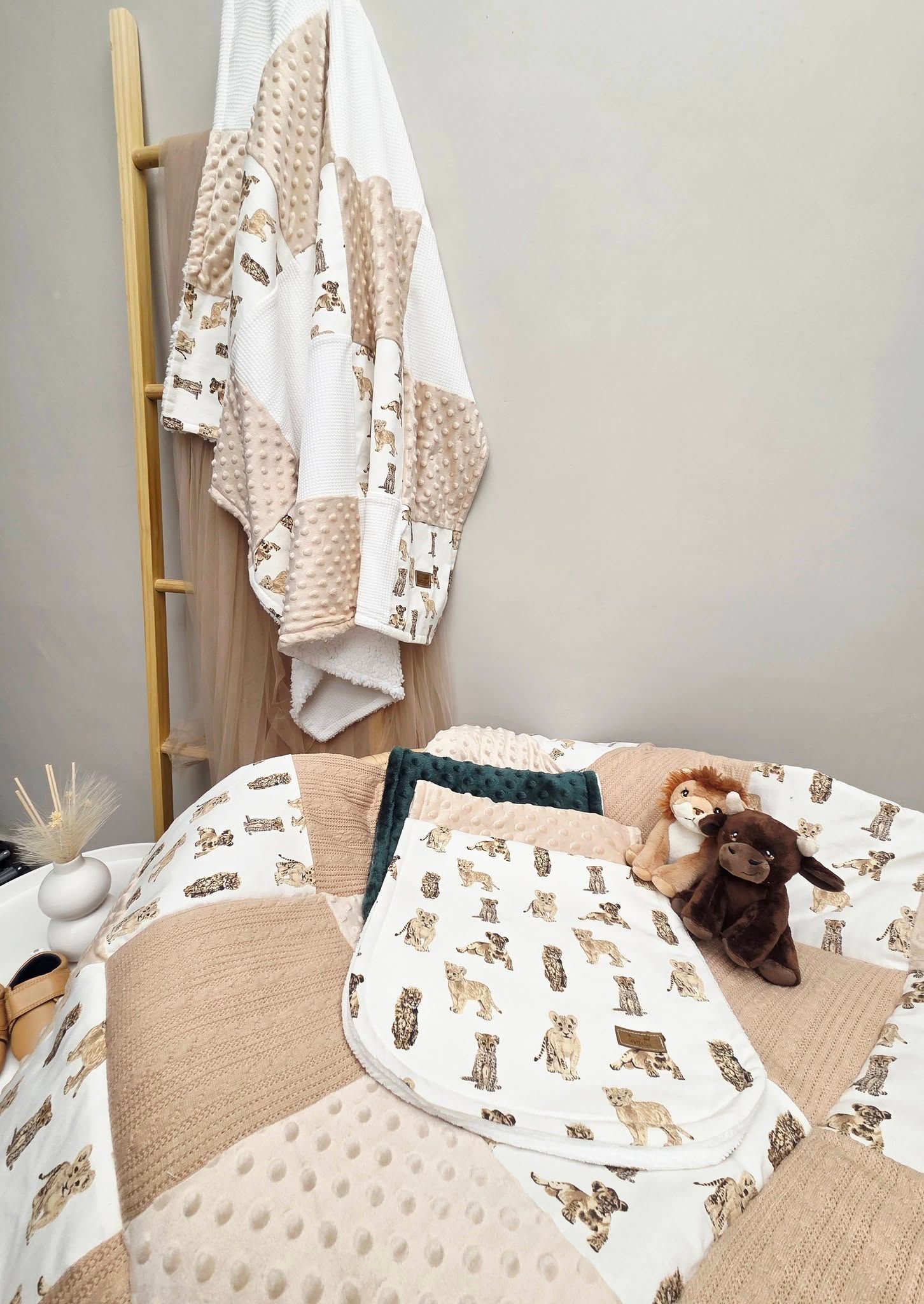 Neutral nursery set with woodland animal print blankets, minky dot accents, and plush toys on a changing table.