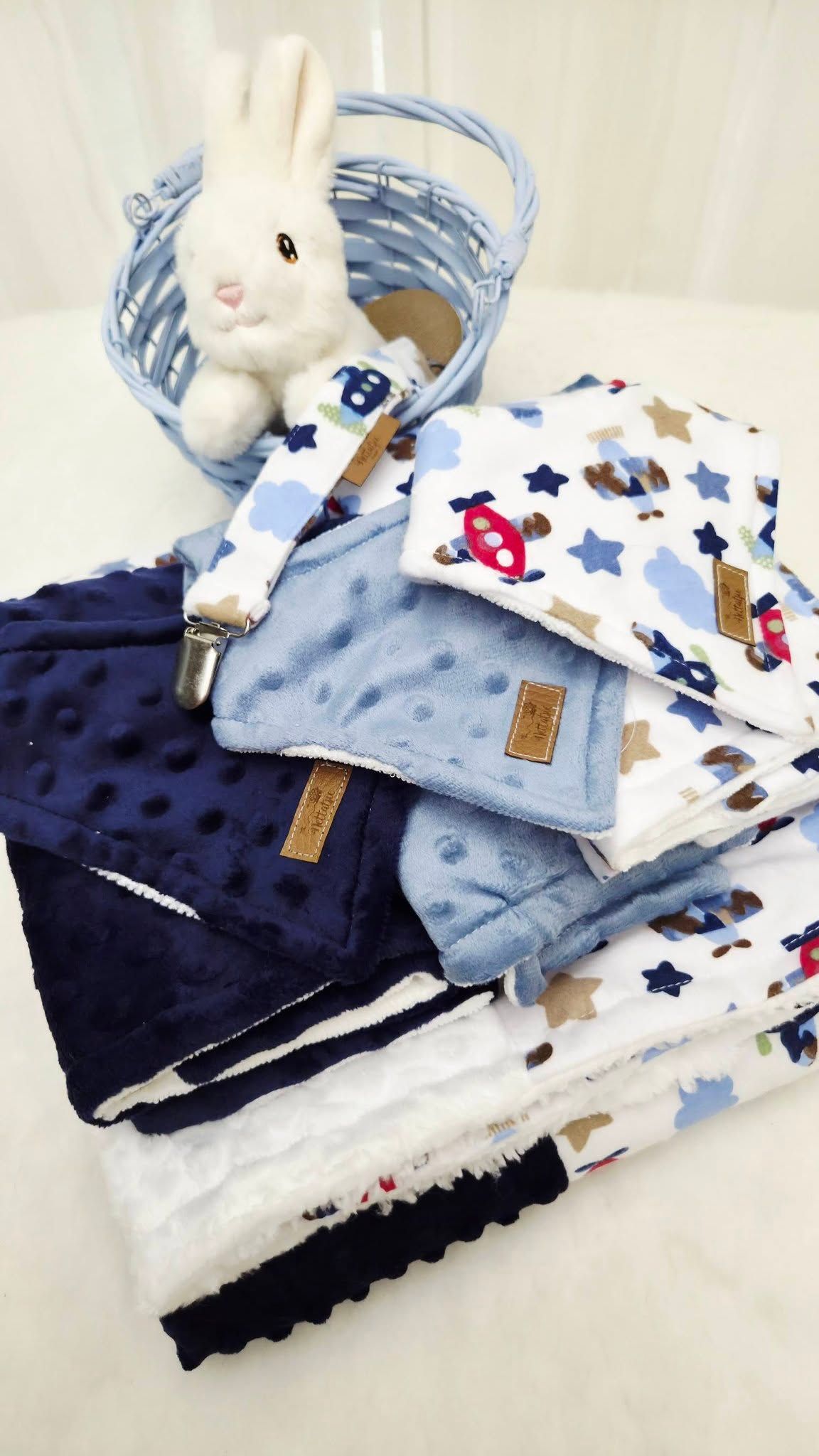Blue baby gift basket with minky blanket, airplane print items, pacifier clip, and white plush bunny toy.