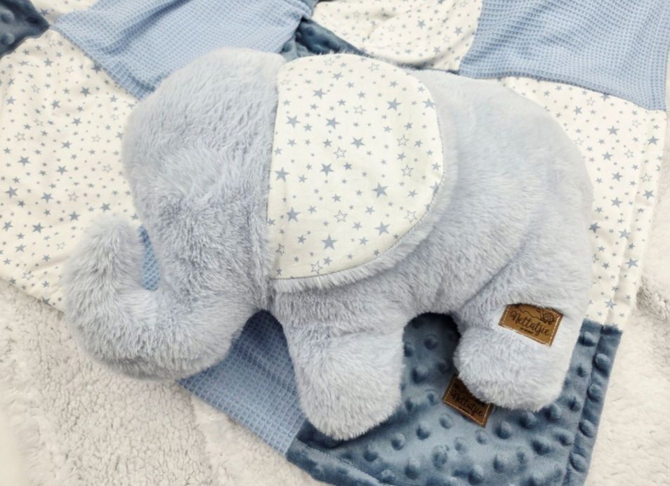 Blue plush elephant stuffed animal toy resting on a star-patterned baby blanket set.
