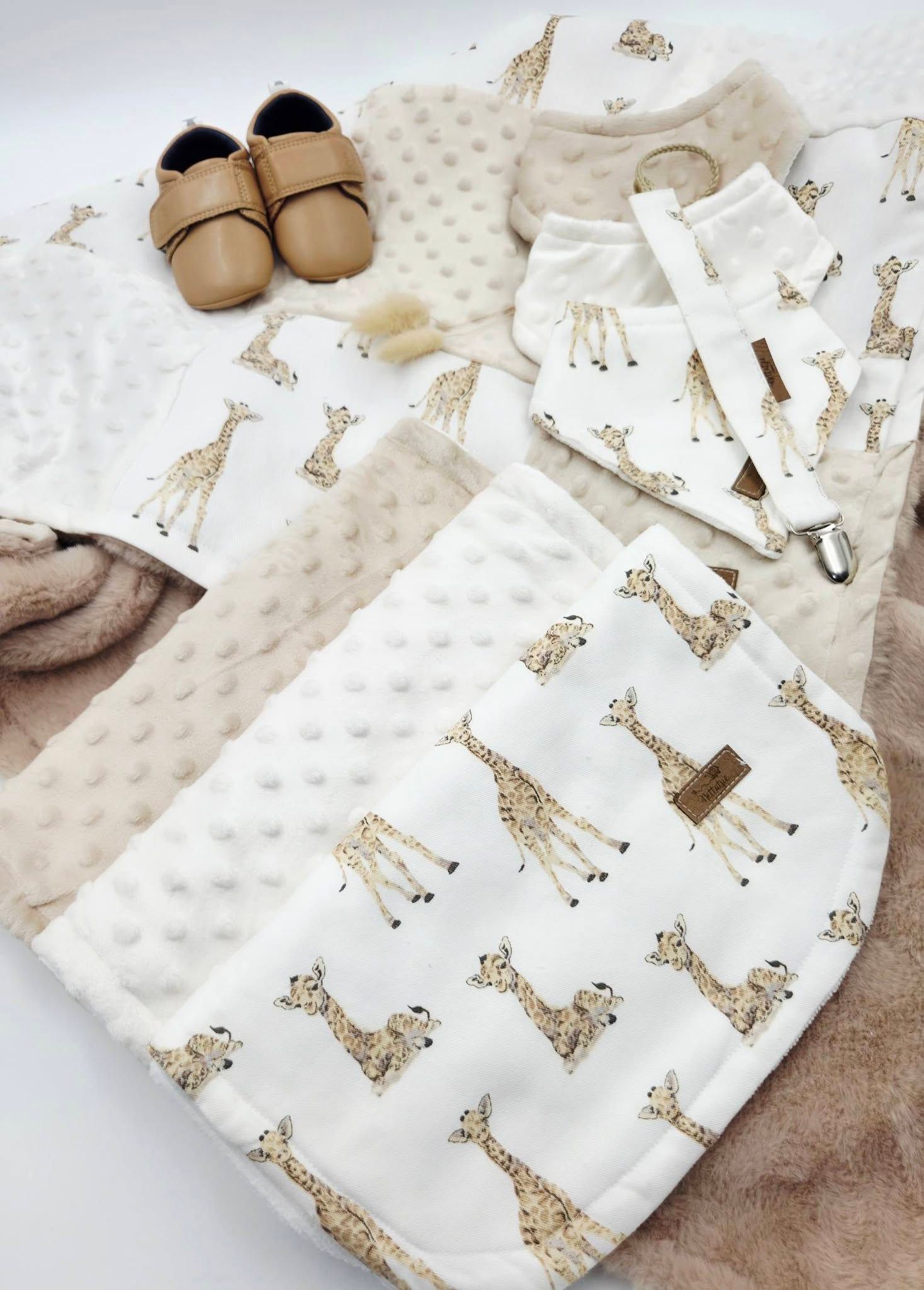 Baby giraffe print blanket set with minky dot fabric, bib, pacifier clip, and tan leather shoes in neutral beige tones.