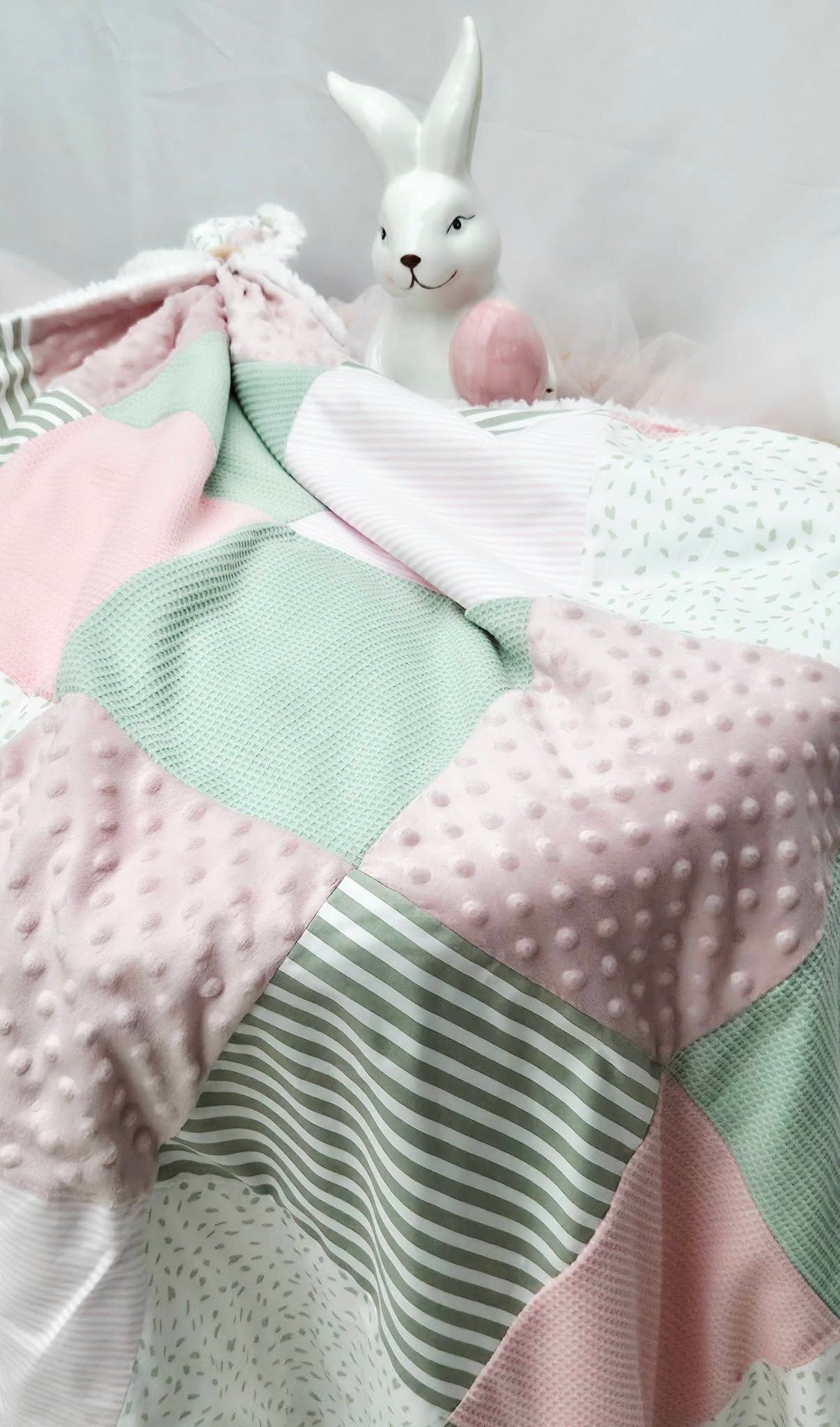 Mint and pink patchwork baby quilt with bunny figurine and Easter egg decoration.