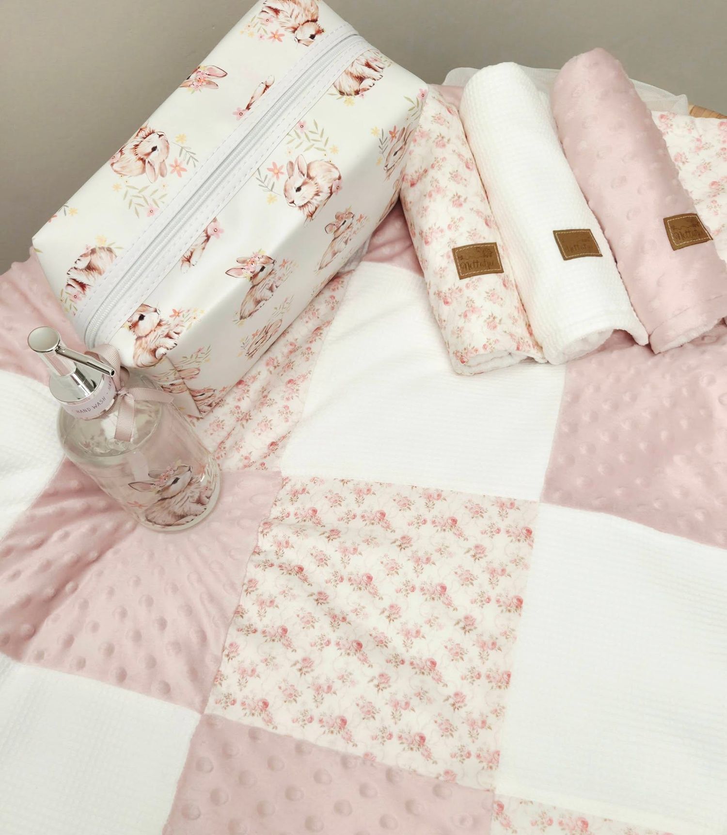 Pink floral baby quilt set with matching zipper pouch, burp cloths, and minky dot fabric squares in soft blush tones.