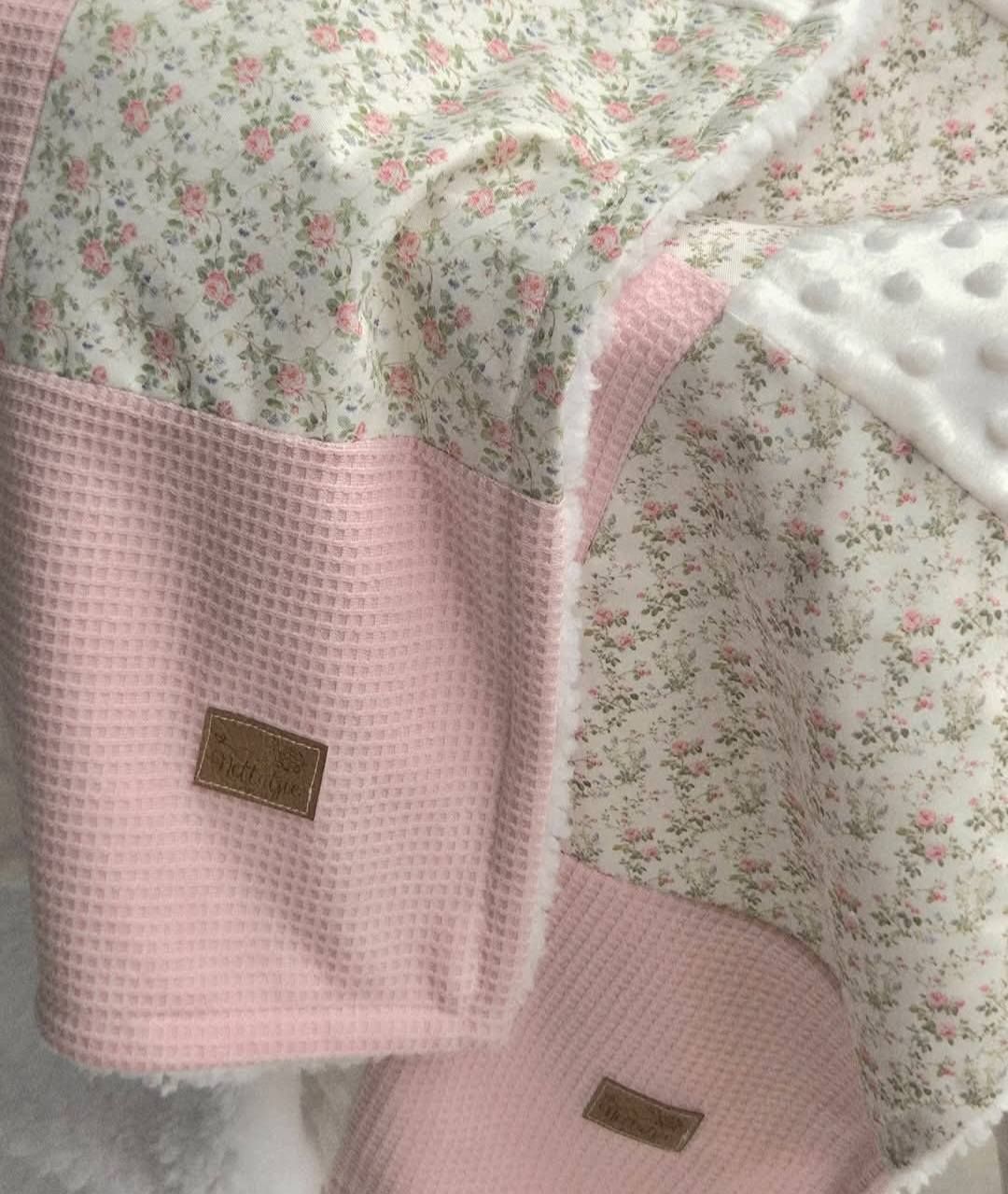 Pink waffle knit baby blanket with floral print and white minky dot fabric, featuring a small leather logo patch.
