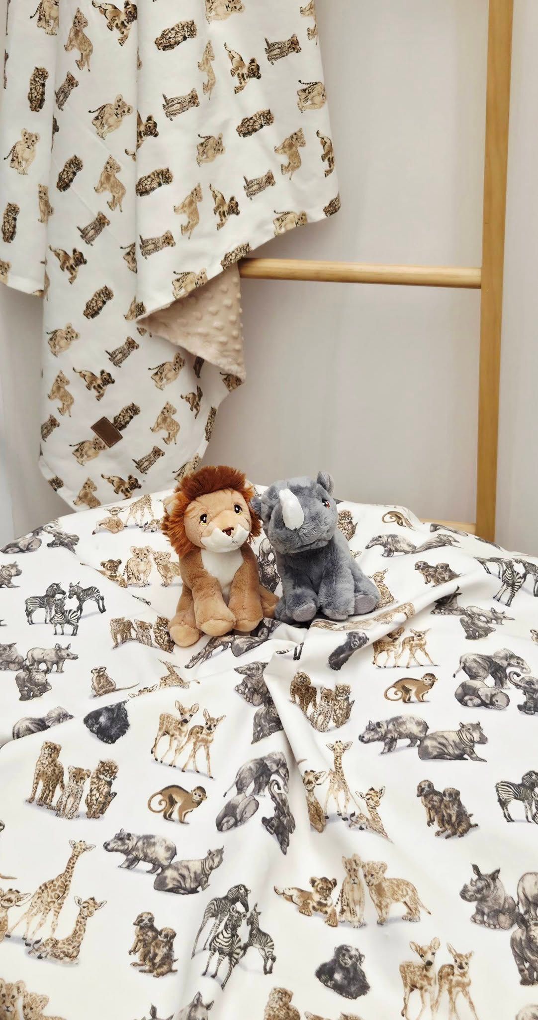 Safari animal print bedding set with matching blanket on rack, featuring plush lion and rhino stuffed toys.