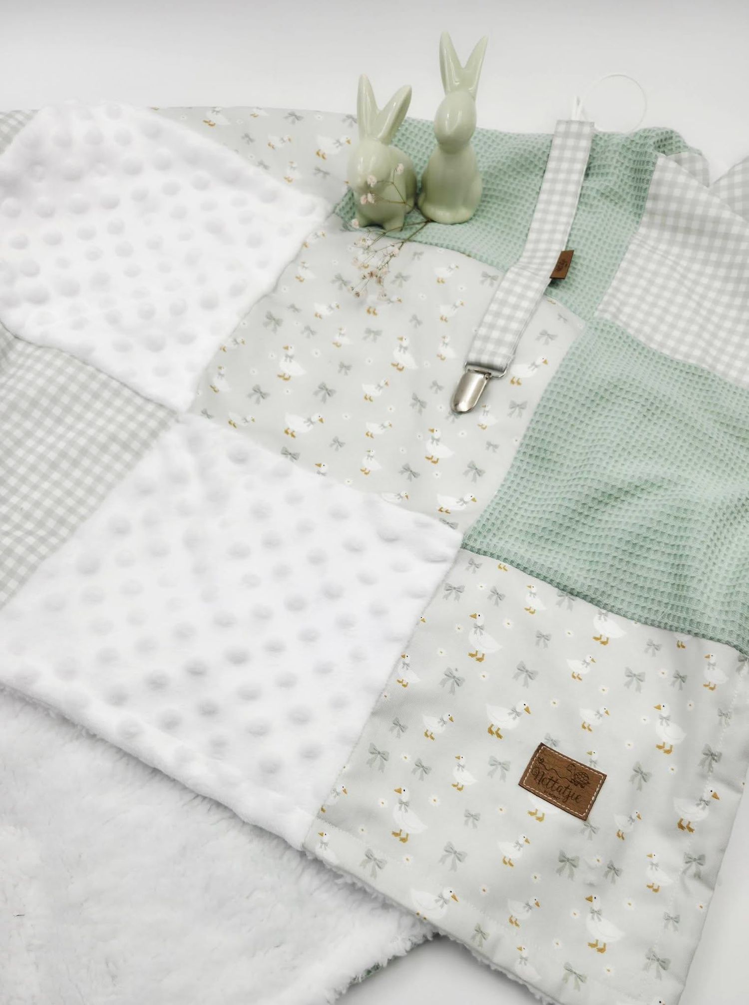 Sage green and white patchwork baby blanket with bunny motifs, waffle texture, and plush minky fabric squares.