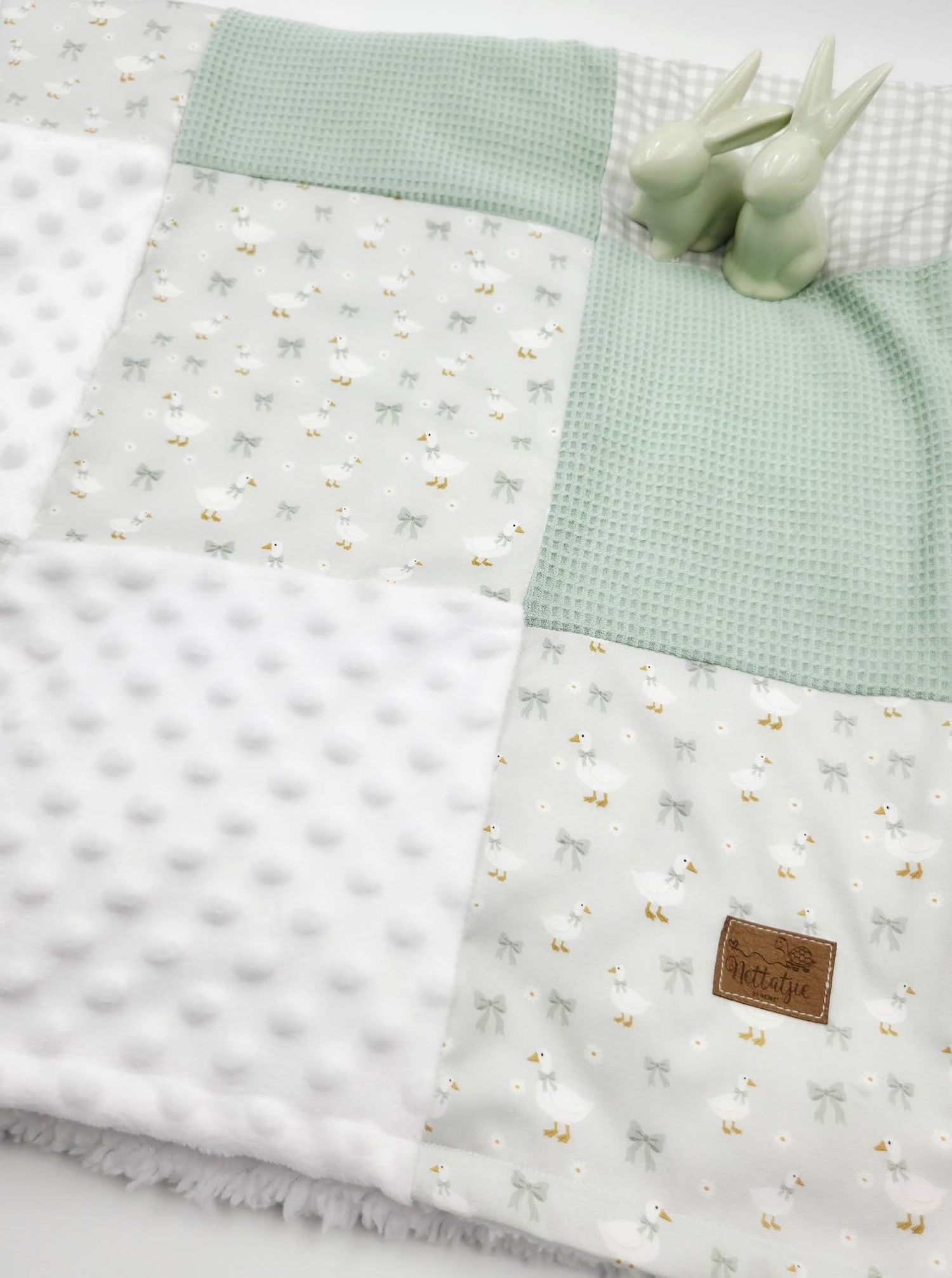 Soft patchwork baby blanket in mint green and white with bunny print, waffle knit, and minky dot fabric textures.