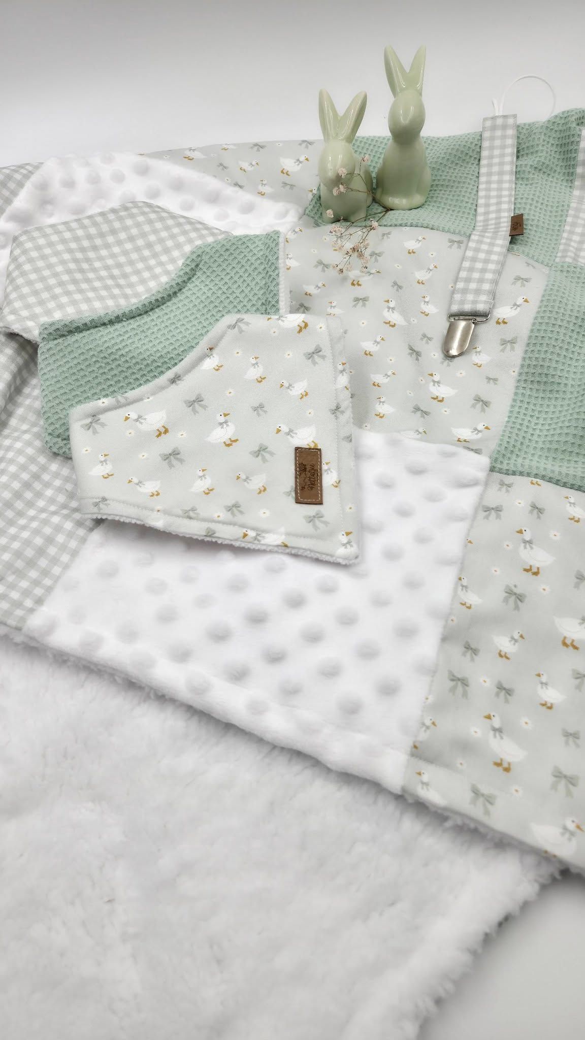 Sage green baby gift set with patchwork blanket, bib, and bunny figurine featuring soft minky fabric and floral print.