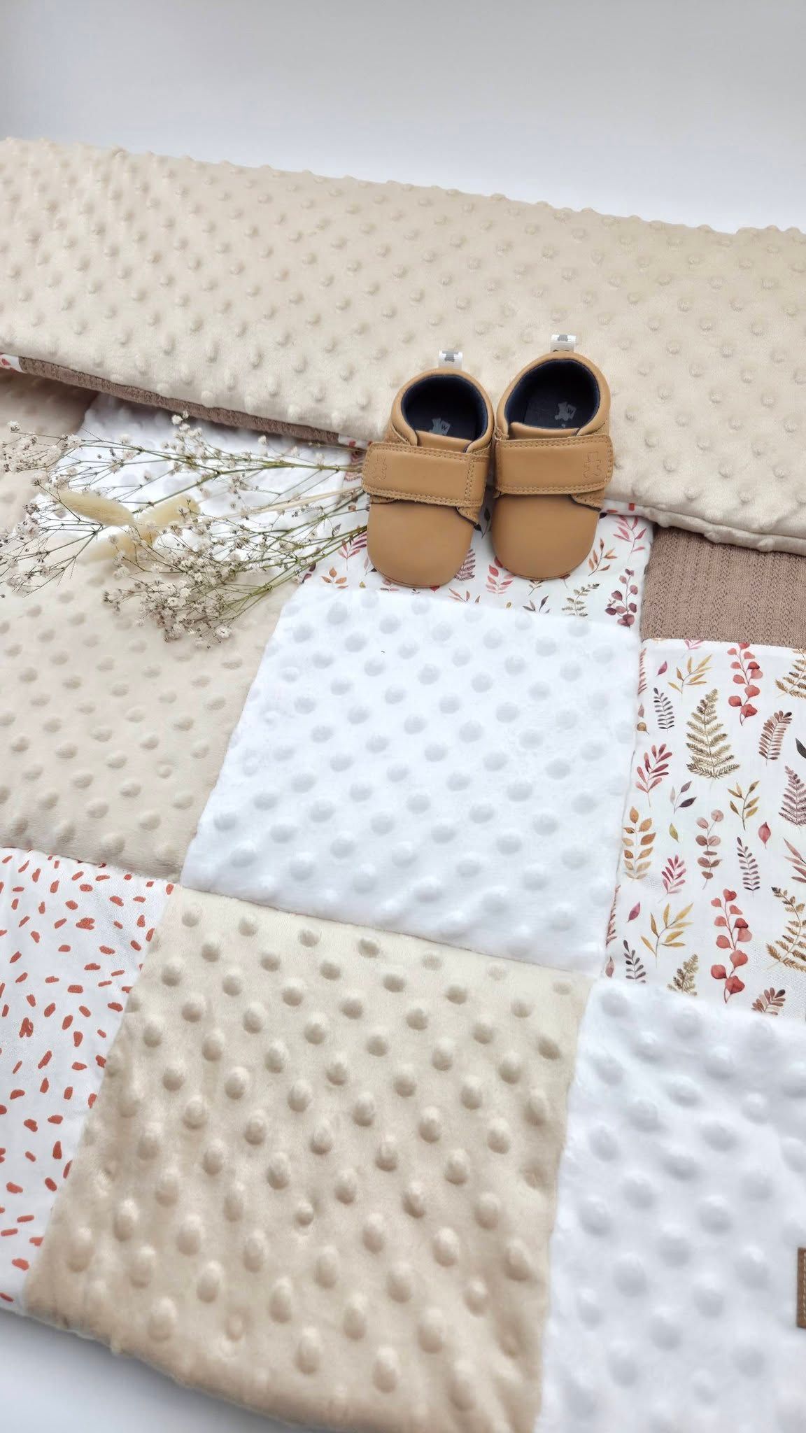 Neutral toned baby patchwork play mat with minky dot texture and tan leather baby moccasins, autumn leaf print.