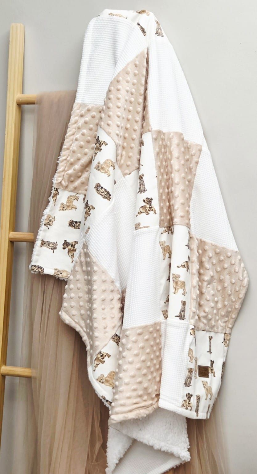 Soft beige minky blankets with teddy bear print patterns hanging on wooden ladder display.