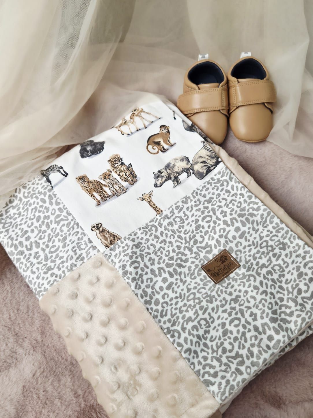 Baby shoes and blankets with leopard print patterns and minky dot textures arranged in a soft, neutral color palette.