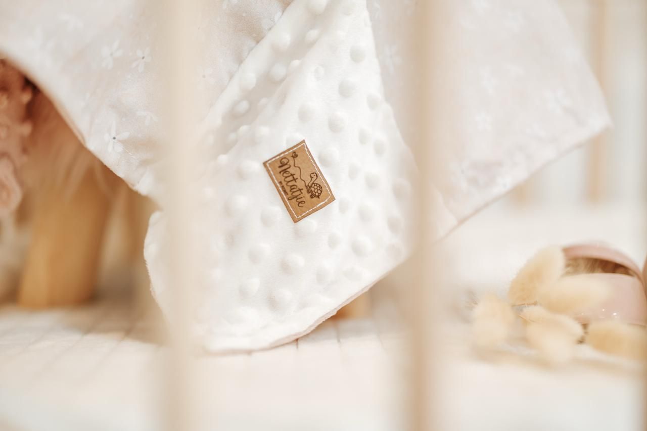 A close-up view of delicate white lace fabric with intricate floral patterns and textures.