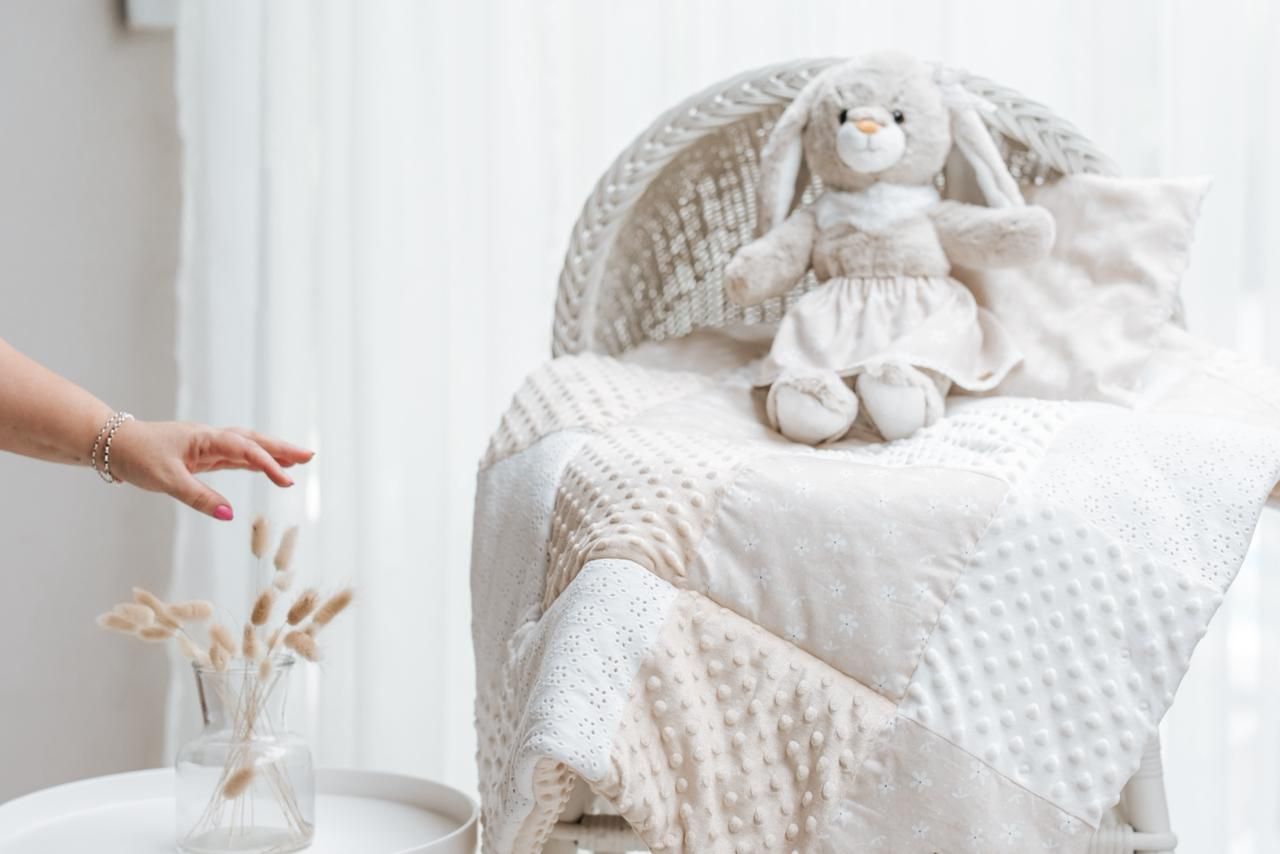 White ceramic bunny figurine sits atop a textured knit blanket in soft neutral tones.