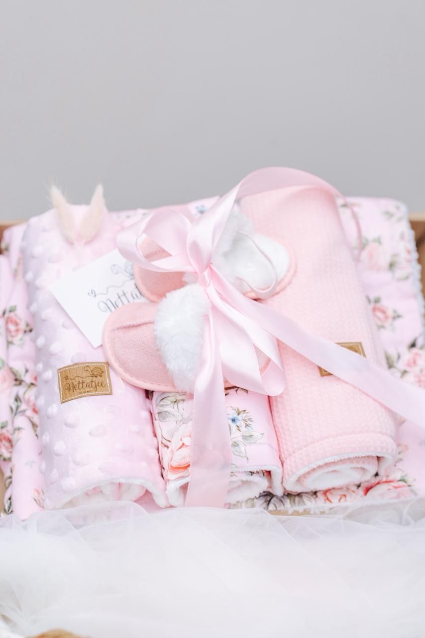 Pink baby blanket set with floral patterns tied with white ribbon.