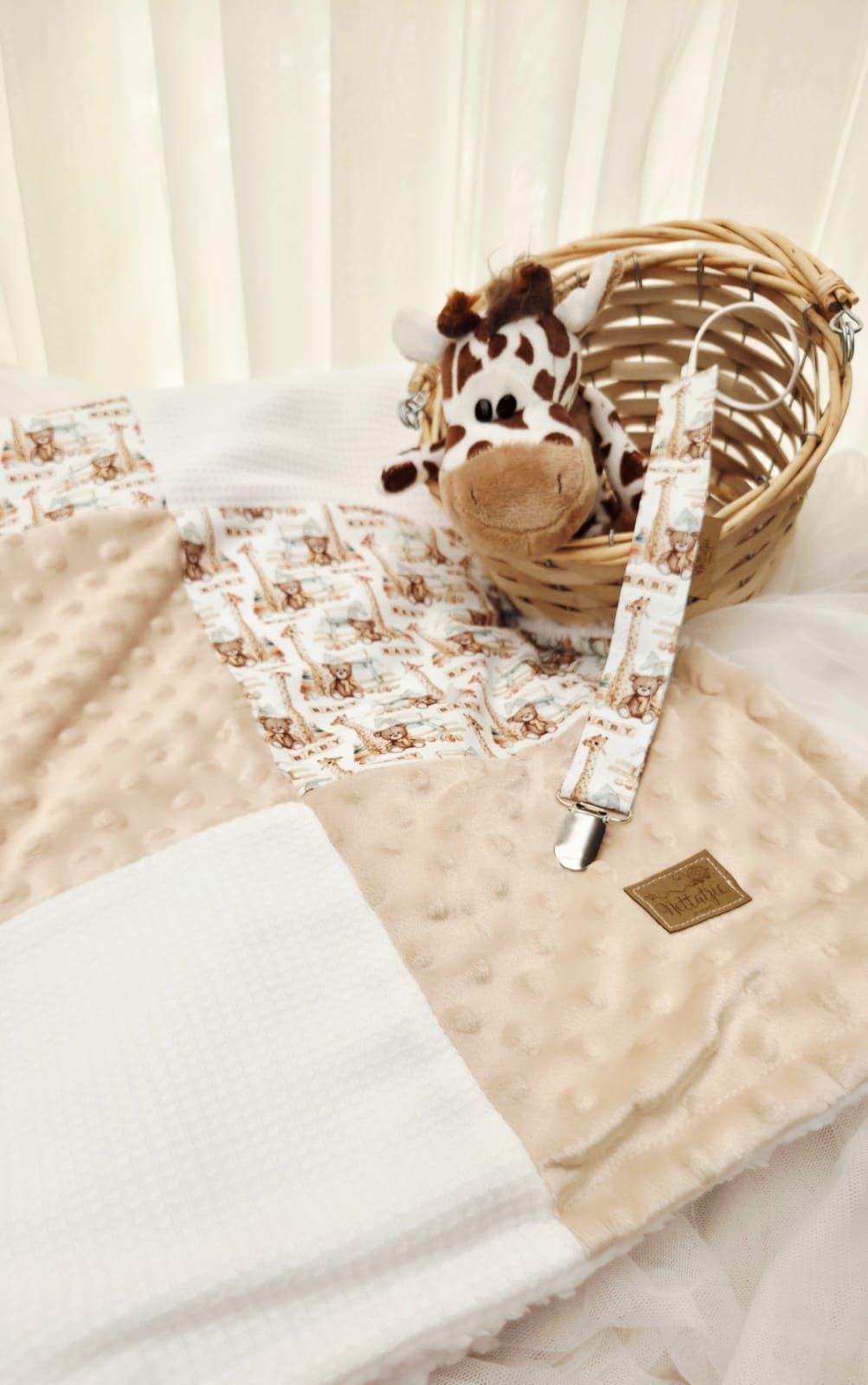 Woven basket and white textiles with delicate floral patterns arranged on a light beige surface in soft natural lighting.