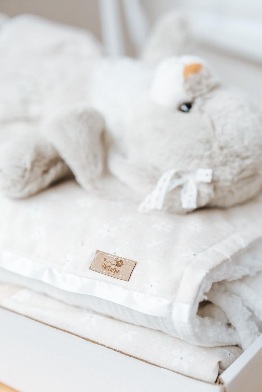 Soft white plush toy and folded towels with a small beige label on white surface.