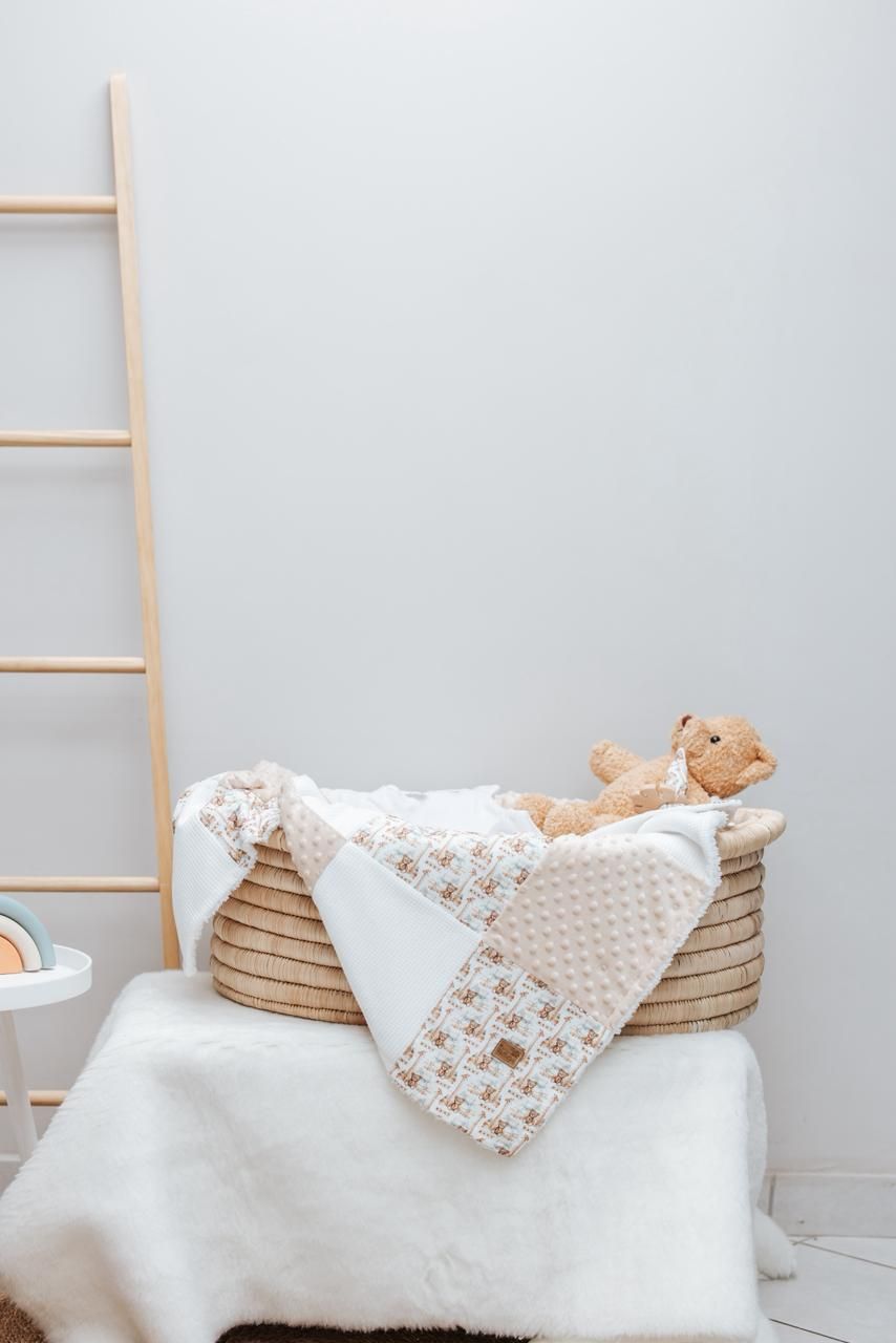 Woven basket with white and patterned baby blankets and plush toy.