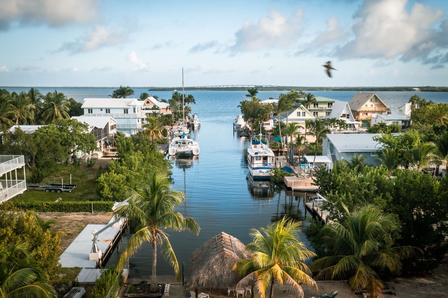 Aerial panoramic view of waterfront homes and docks along the Florida Keys coastline on a sunny day with blue waters.