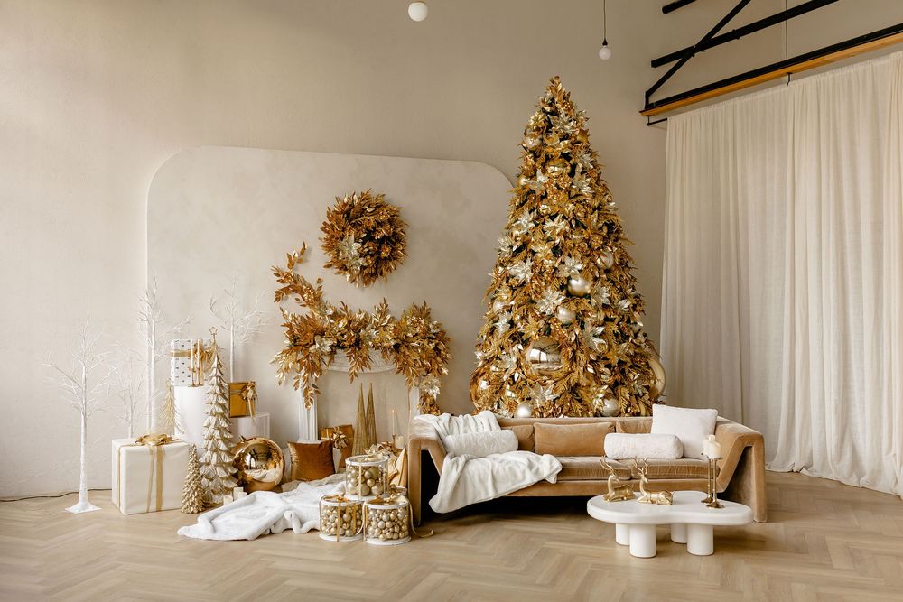 Elegant Christmas decor with gold ornaments and white tree surrounded by wrapped presents in a minimalist setting.