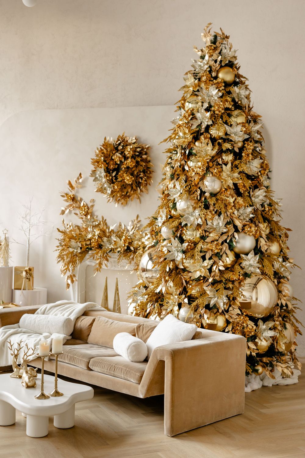Modern living room with multiple gold-decorated Christmas trees, white and beige decor, and elegant holiday accents.