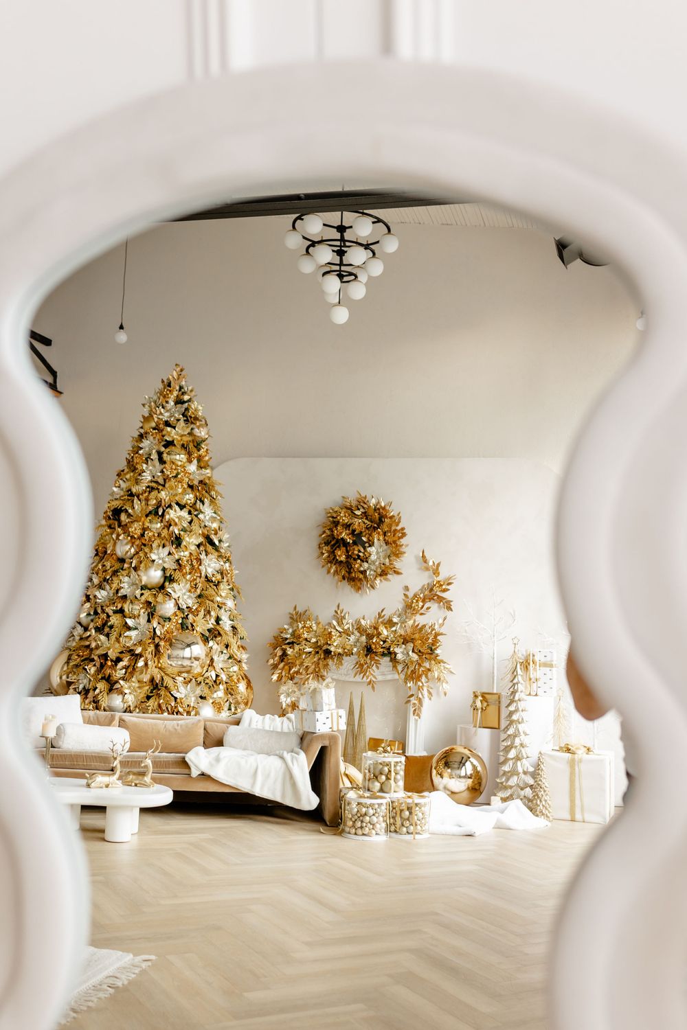 White archway view of an elegant Christmas display featuring golden trees and holiday decorations.