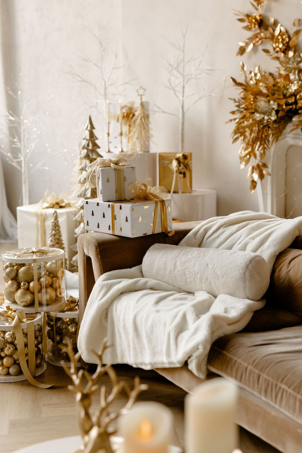 Cozy living room decorated in white and gold with Christmas ornaments, pillows, and throws on a comfortable couch.