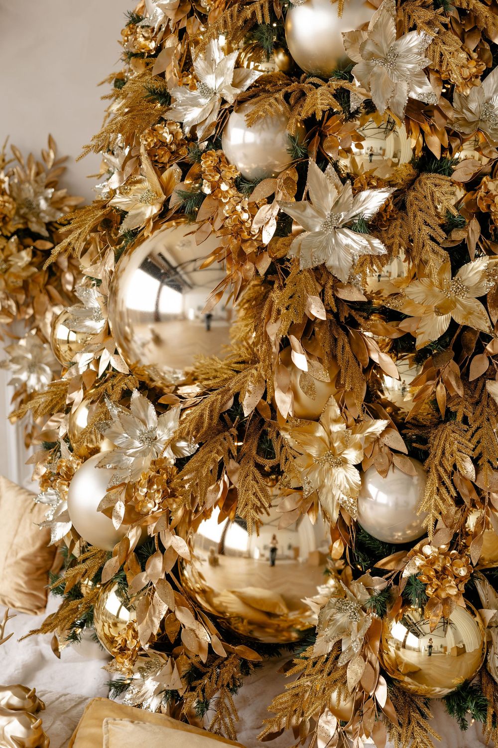 Close-up of a luxurious Christmas tree decorated with gold and silver ornaments, baubles and metallic foliage.