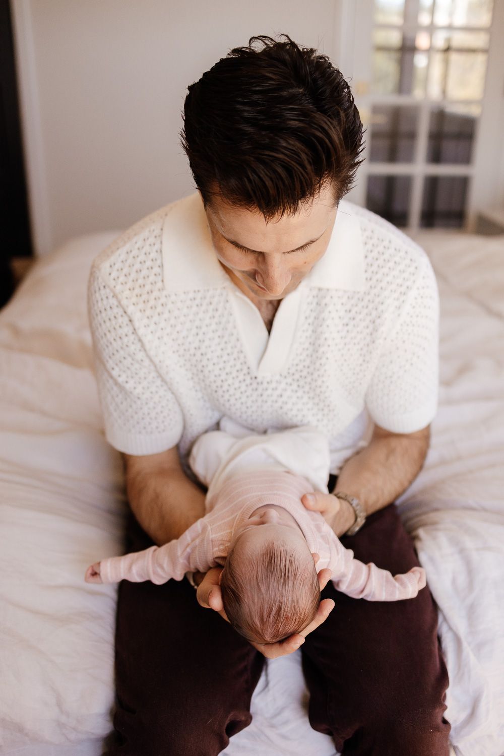 a dad looks at his new baby during their in-home baby photoshoot in the Bay Area