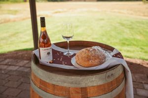 Rustic wooden barrel used as a table on an outdoor patio with a drink and snack plate on top.
