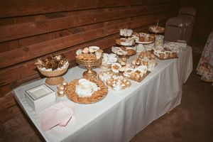 Elegant dessert table with pastries and treats arranged on tiered stands and platters against rustic wooden backdrop.