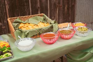Long buffet table set up with various dishes and serving bowls arranged in a rustic outdoor setting.