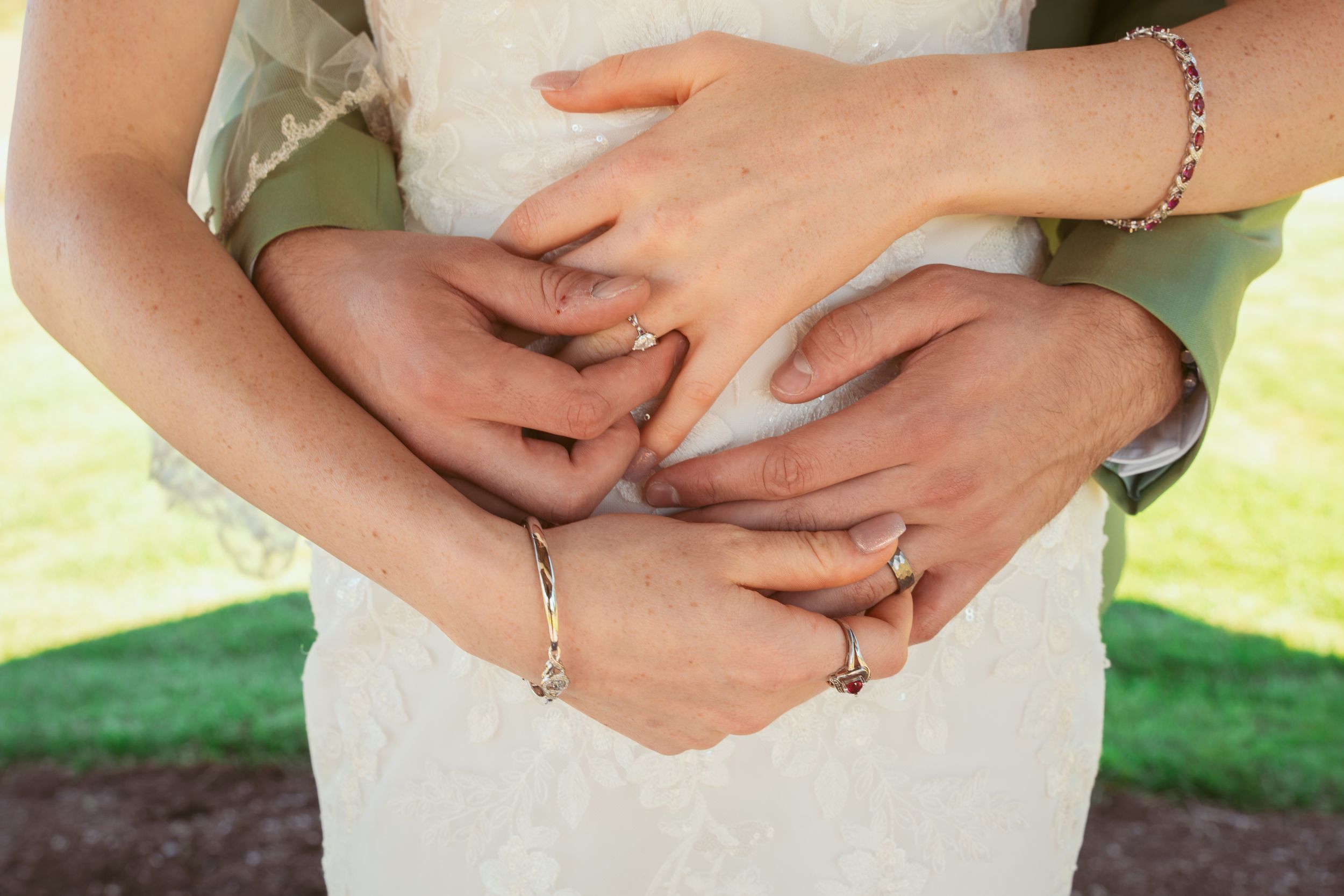 Sequential wedding detail shots of hands clasped together against a white dress and sage green suit.
