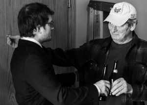 Groom and his father embrace with beers in hand as they celebrate before the ceremony captured in heartfelt black and white moment