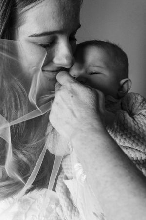 Grandma gently pulling veil away from granddaughter as mom smiles at them both