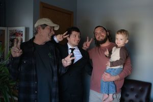Groom, brother, father and nephew giving peace signs to the camera after wedding ceremony