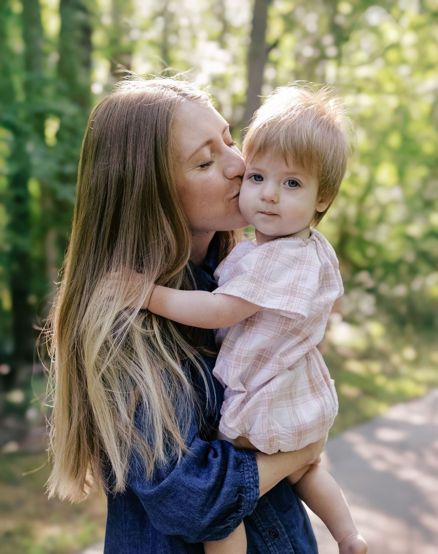 A loving moment between parent and child on a sunny forest path.