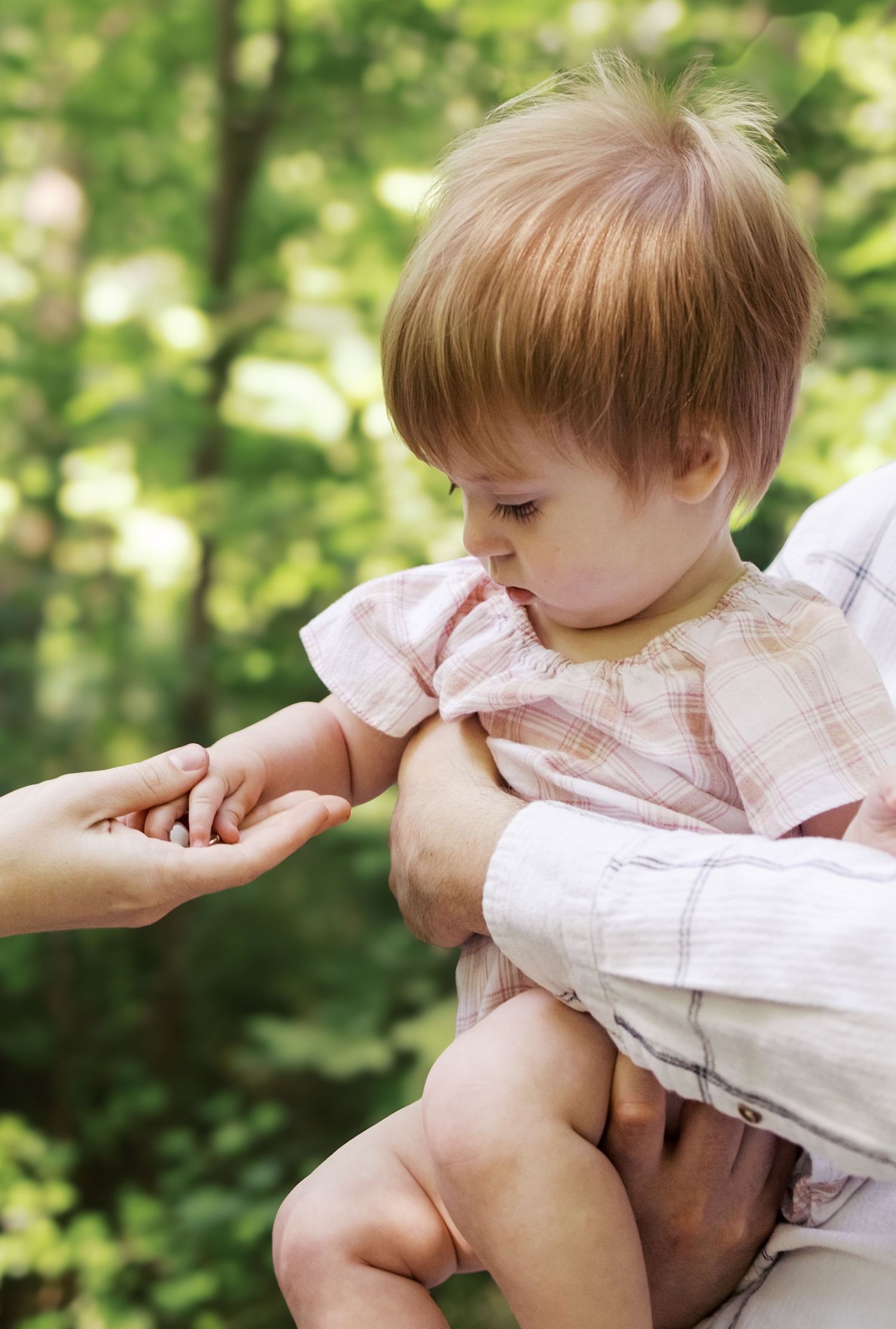 A playful sequence of a baby being tickled outdoors in natural lighting.